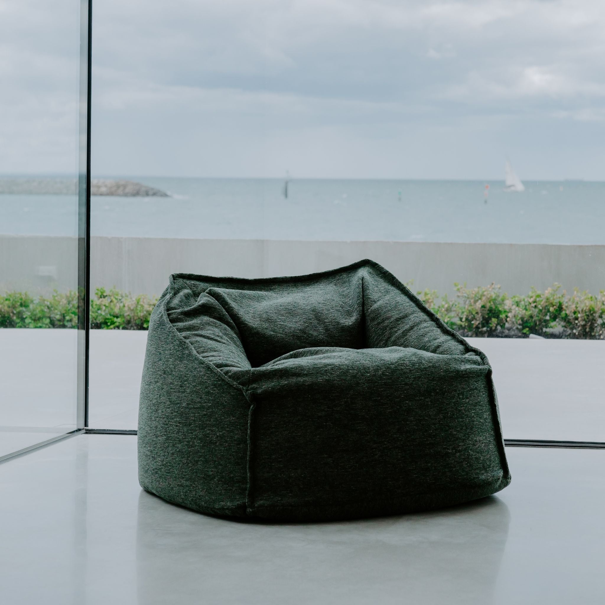 Botanica Green Sabai bean bag chair by ambient lounge in a modern UK indoor setting with large windows.