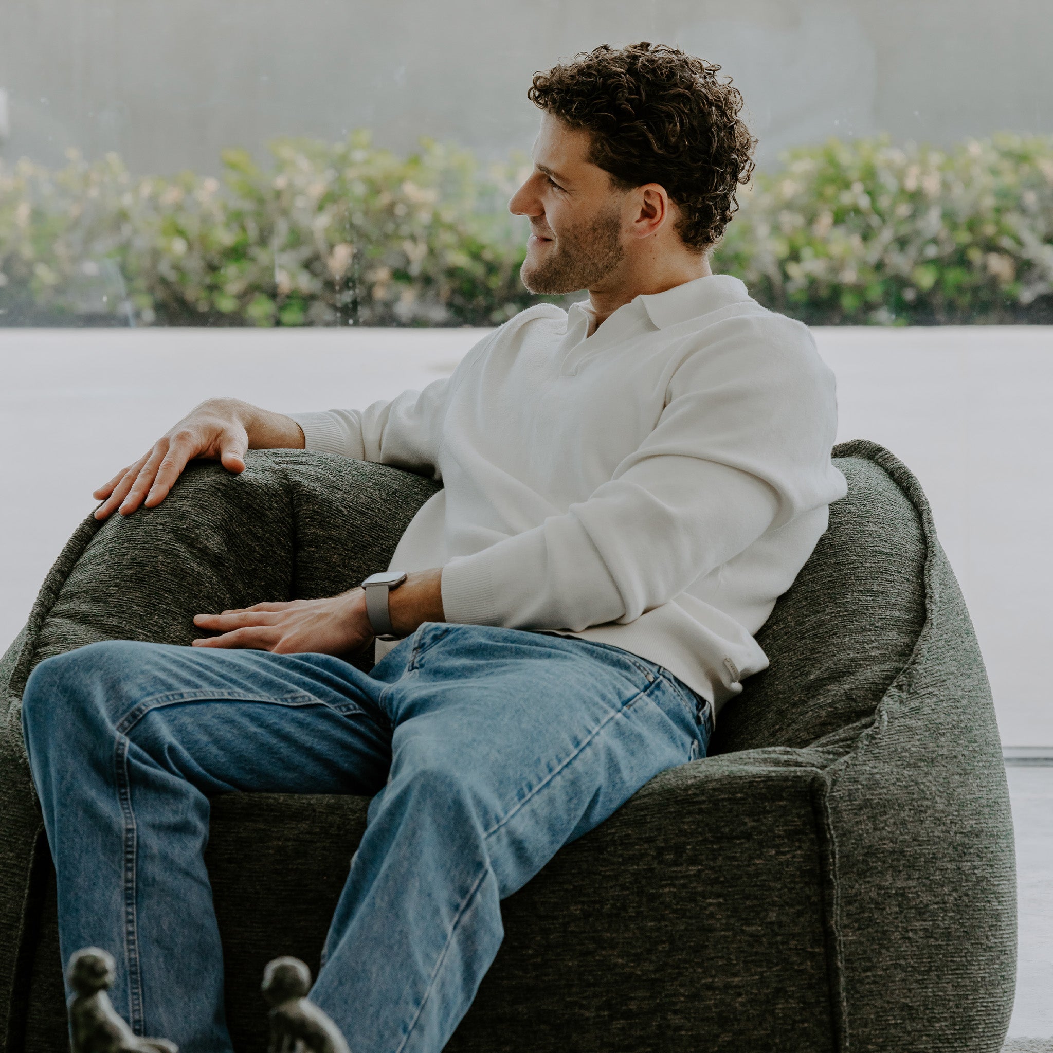 Man sitting comfortably on a green ambient lounge bean bag chair with a blurred outdoor background
